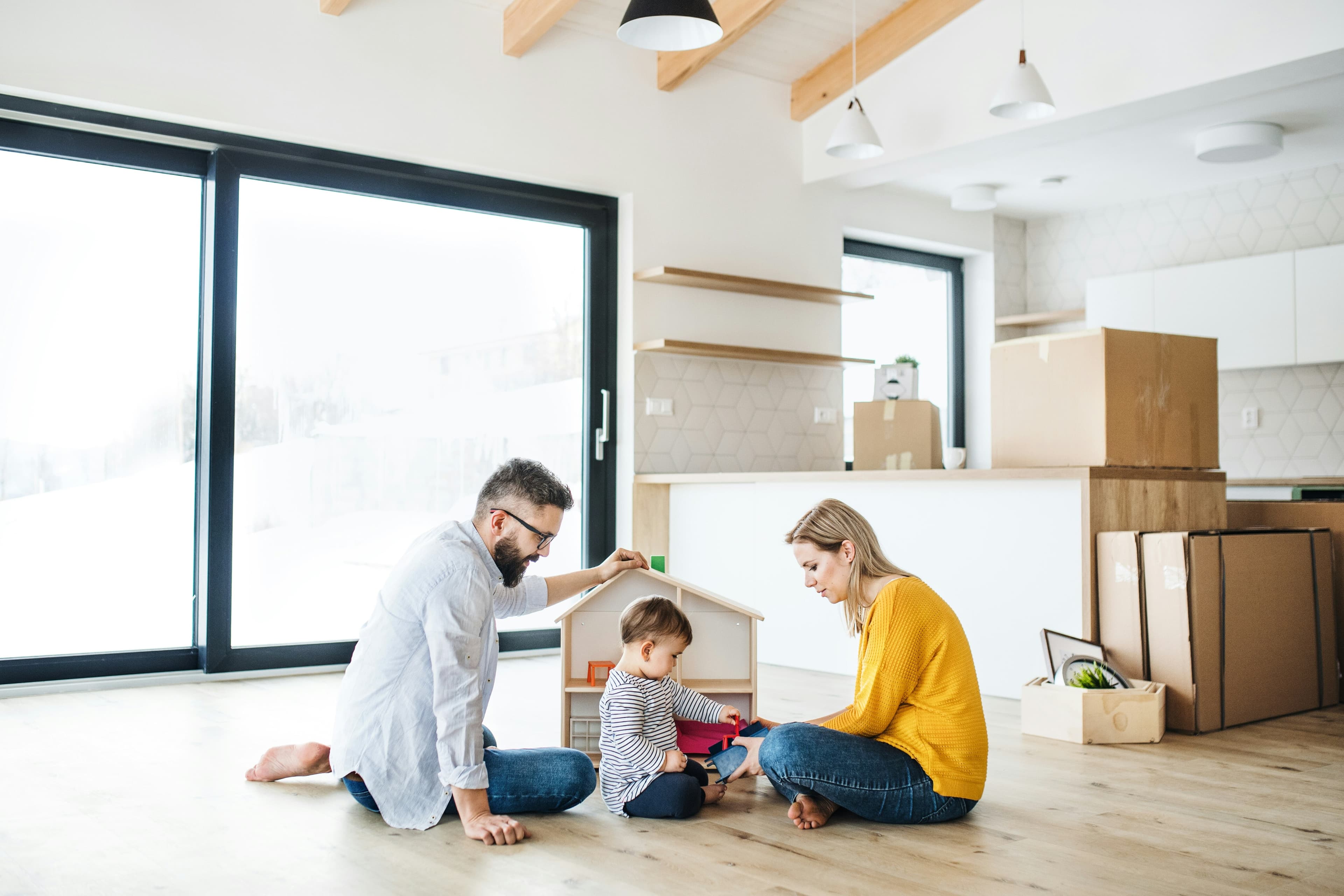 Family on the floor of their home with a wooden toy house, representing home equity