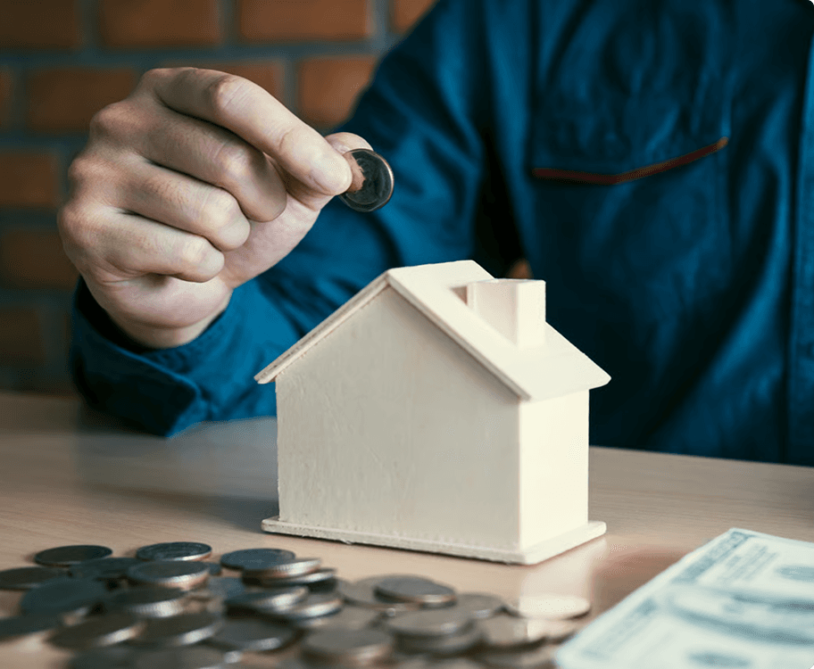 Investor adding a coin to a model house, building a property portfolio with Stryve Finance
